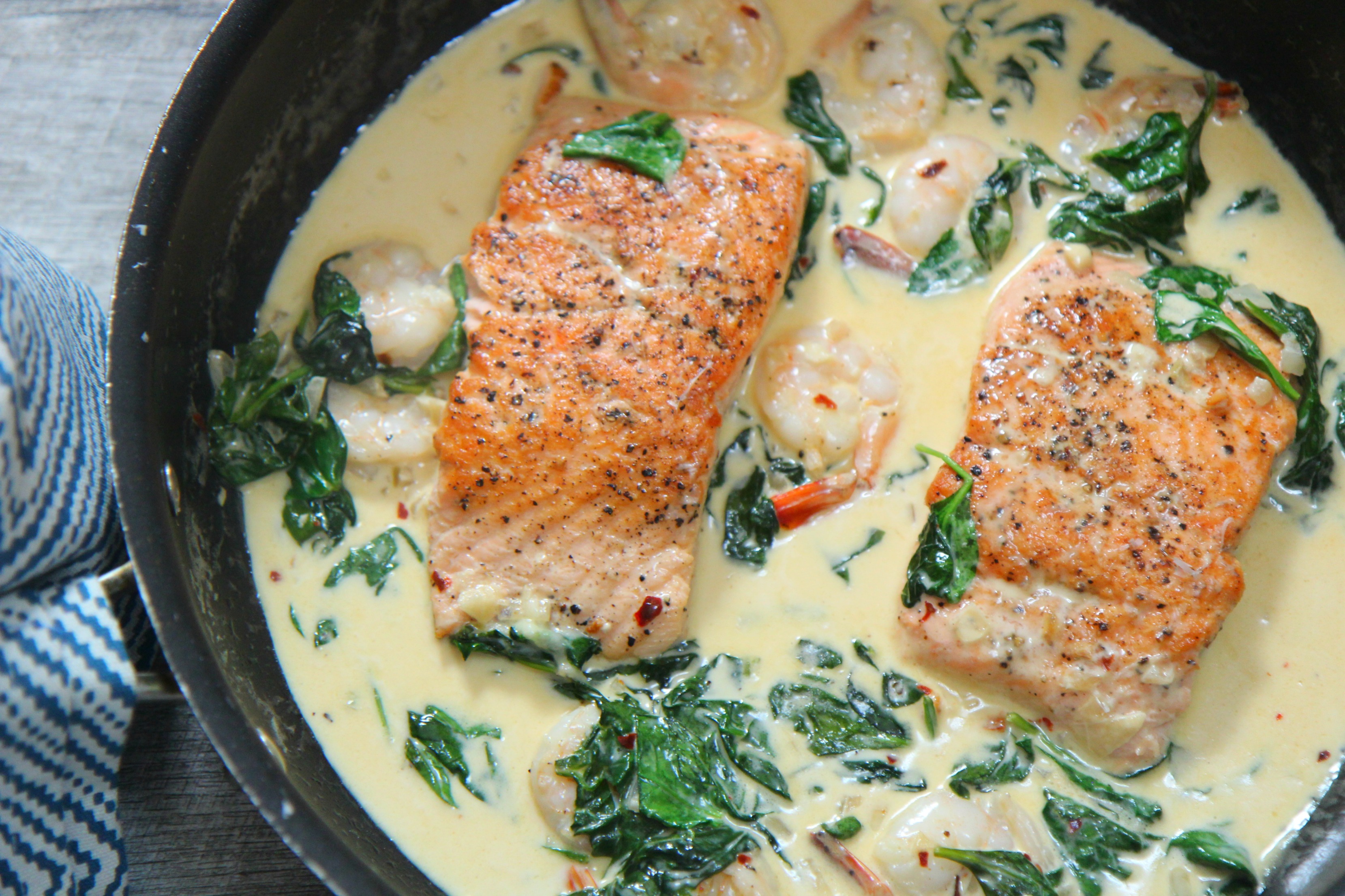 creamy salmon and shrimp in a pot with a blue towel on the side 