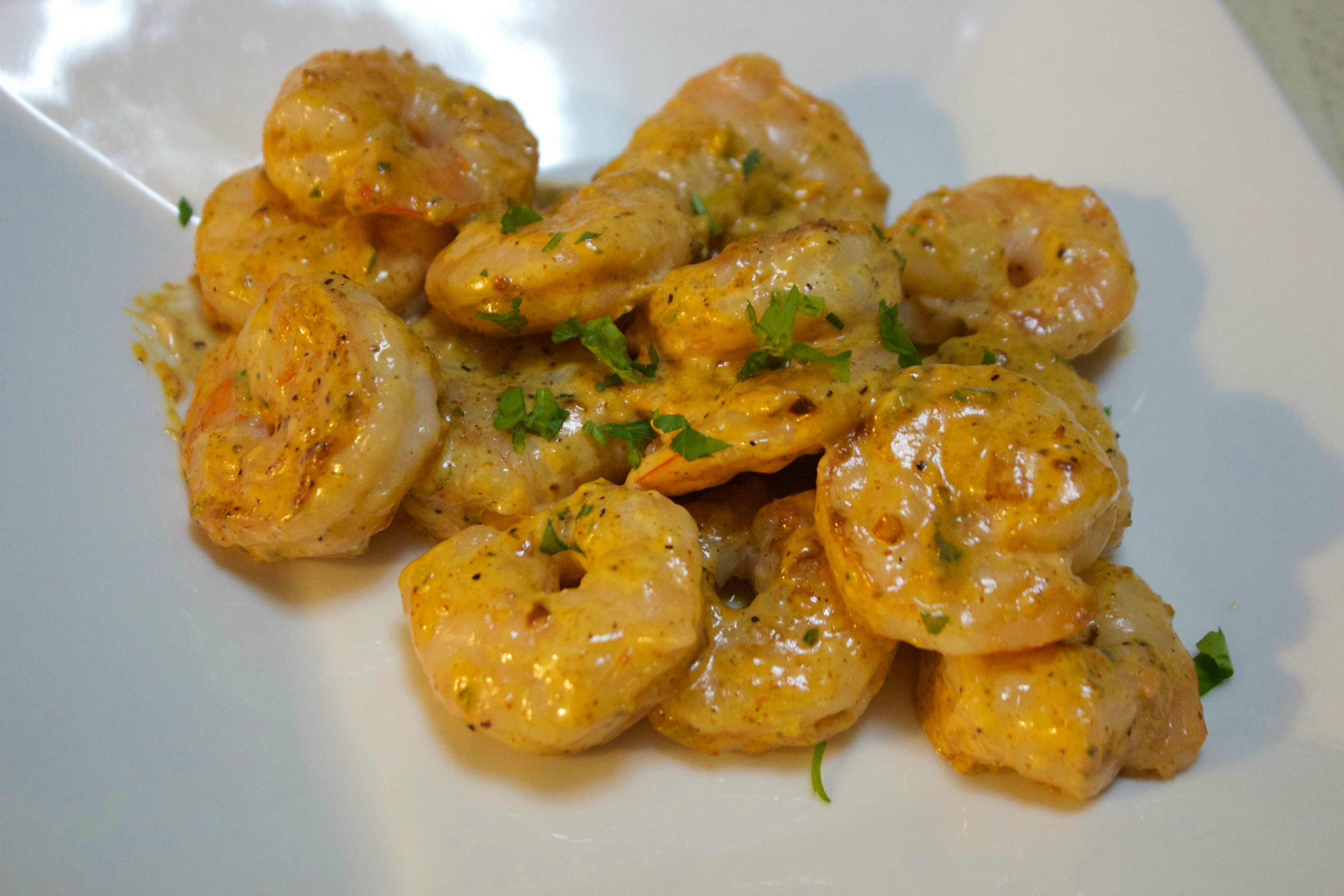 Shrimp coated in a remoulade sauce on a white plate.