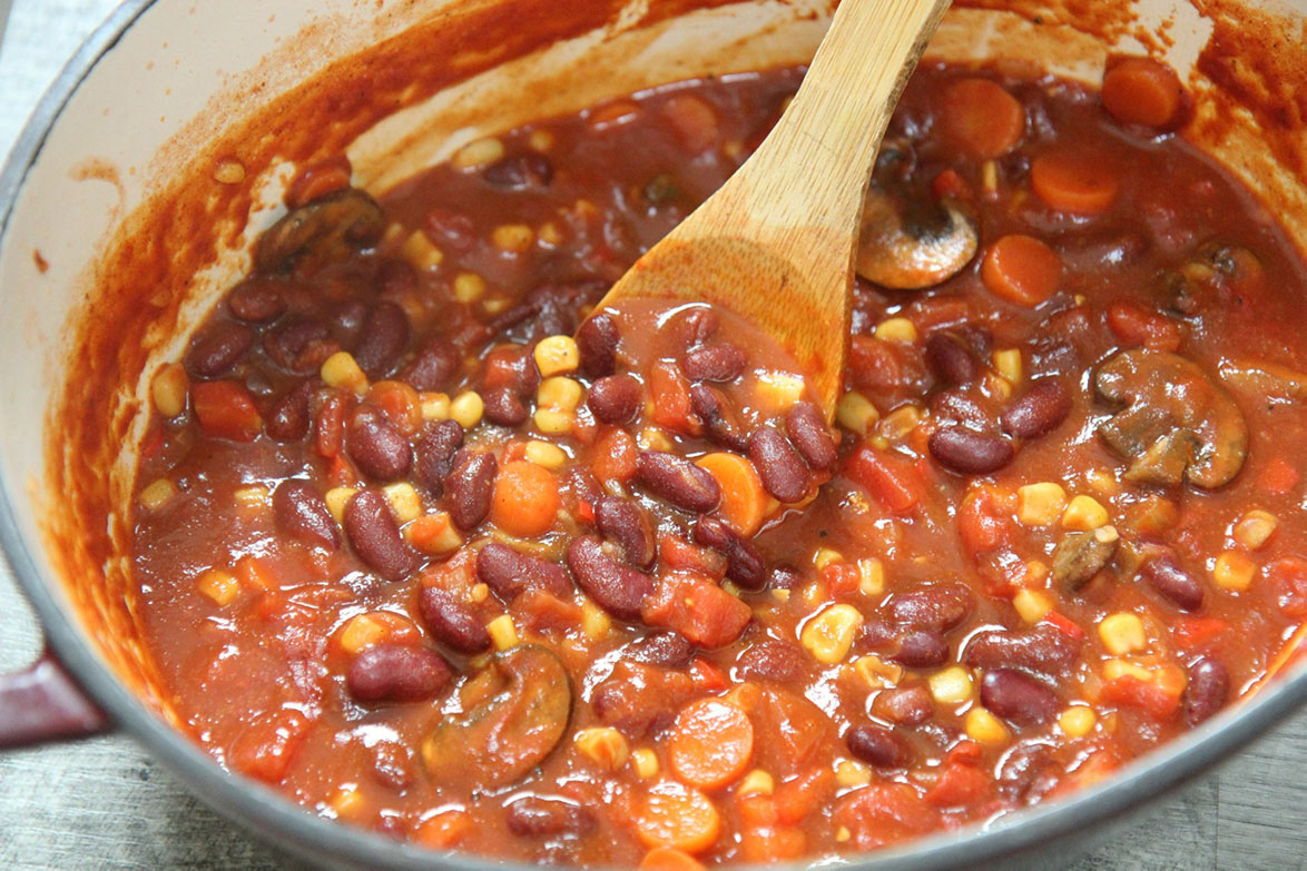 chili in a dutch oven with a wooden spoon 