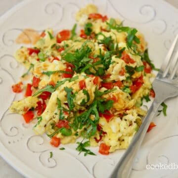 scrambled eggs with peppers and onions. On a plate with a fork.