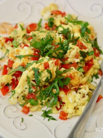 scrambled eggs with peppers and onions. On a plate with a fork.