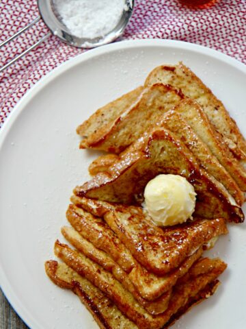 Easy French Toast served with softened butter, powdered sugar, and warm maple syrup.