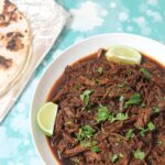 beef barbacoa with lime wedges and cilantro