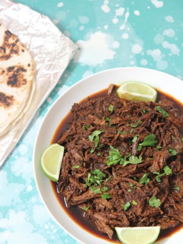 beef barbacoa with lime wedges and cilantro
