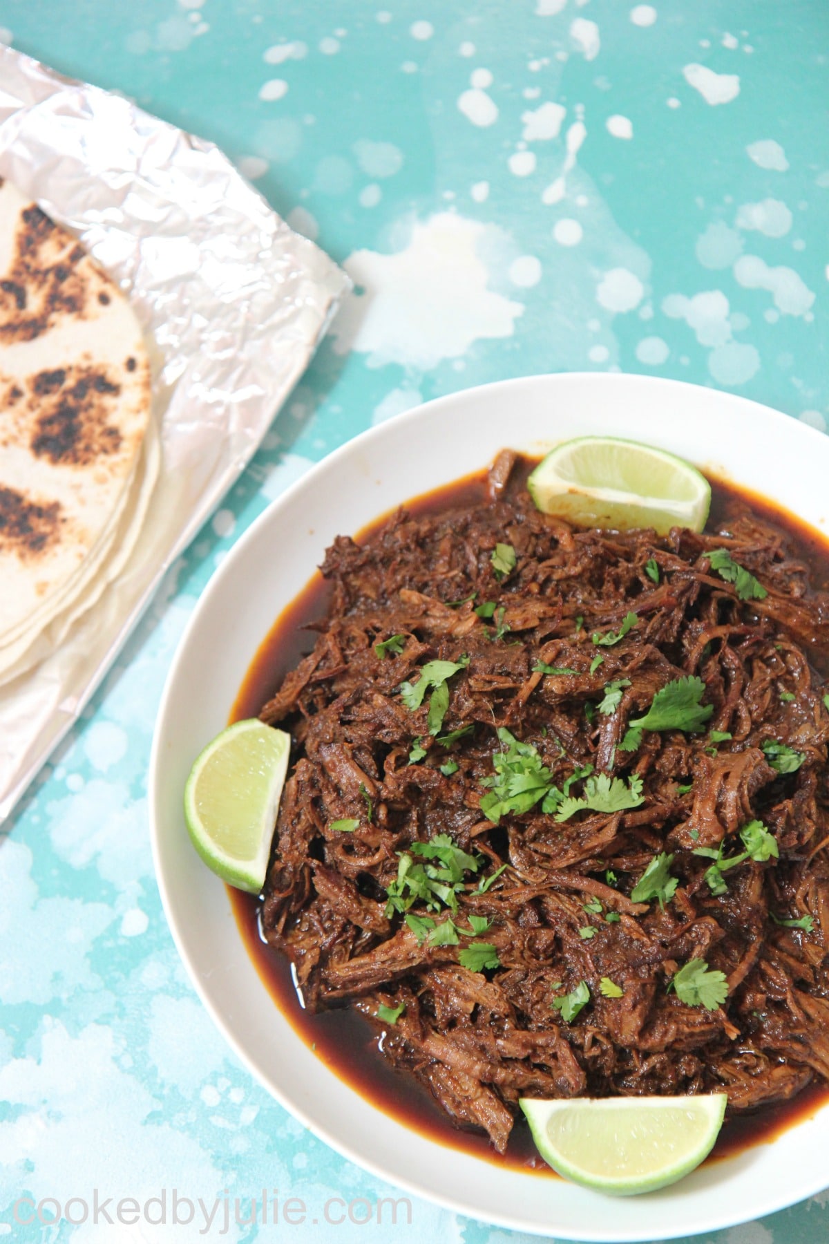 beef barbacoa with lime wedges and cilantro 