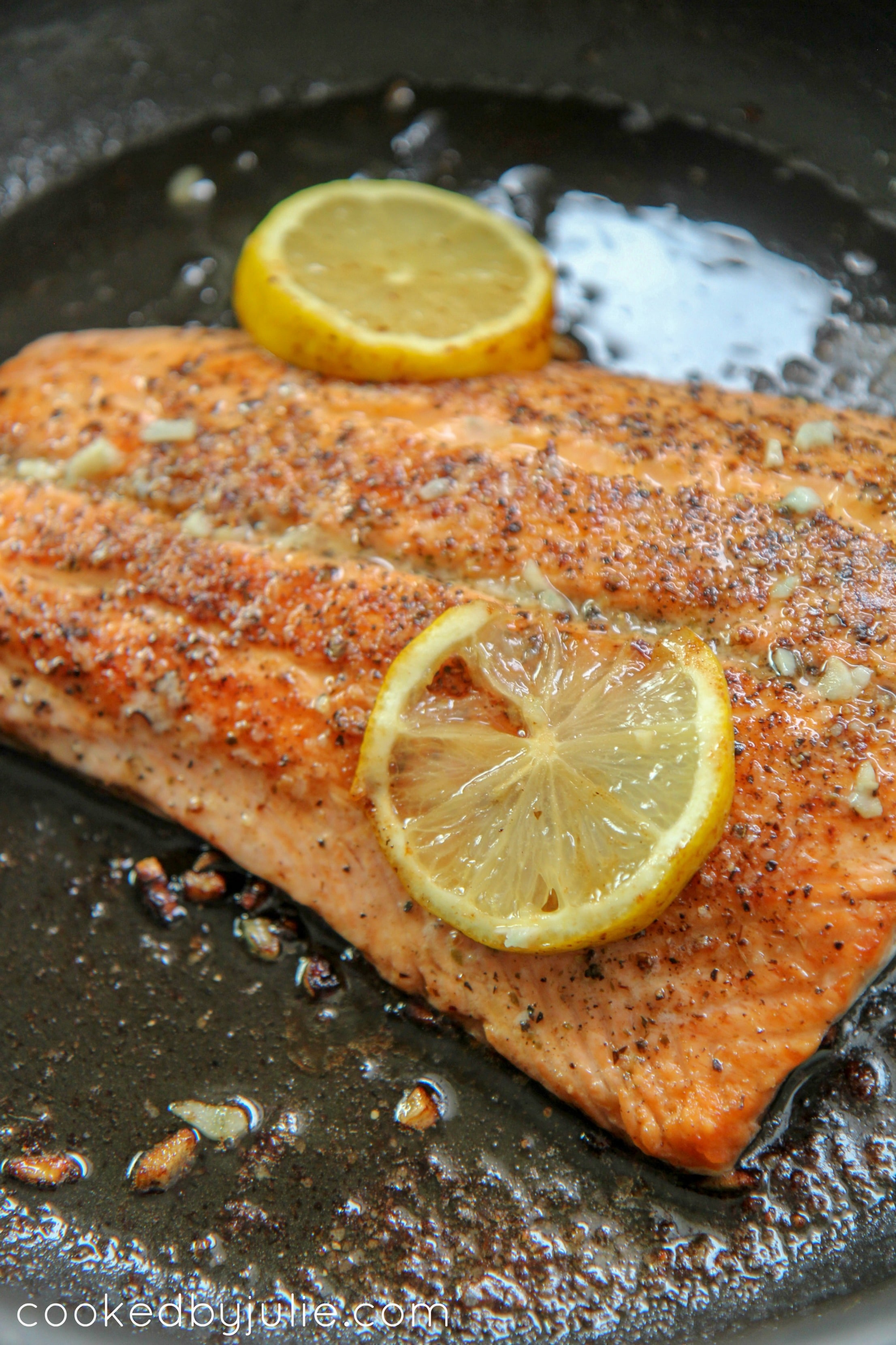 seared salmon with lemon in a black skillet