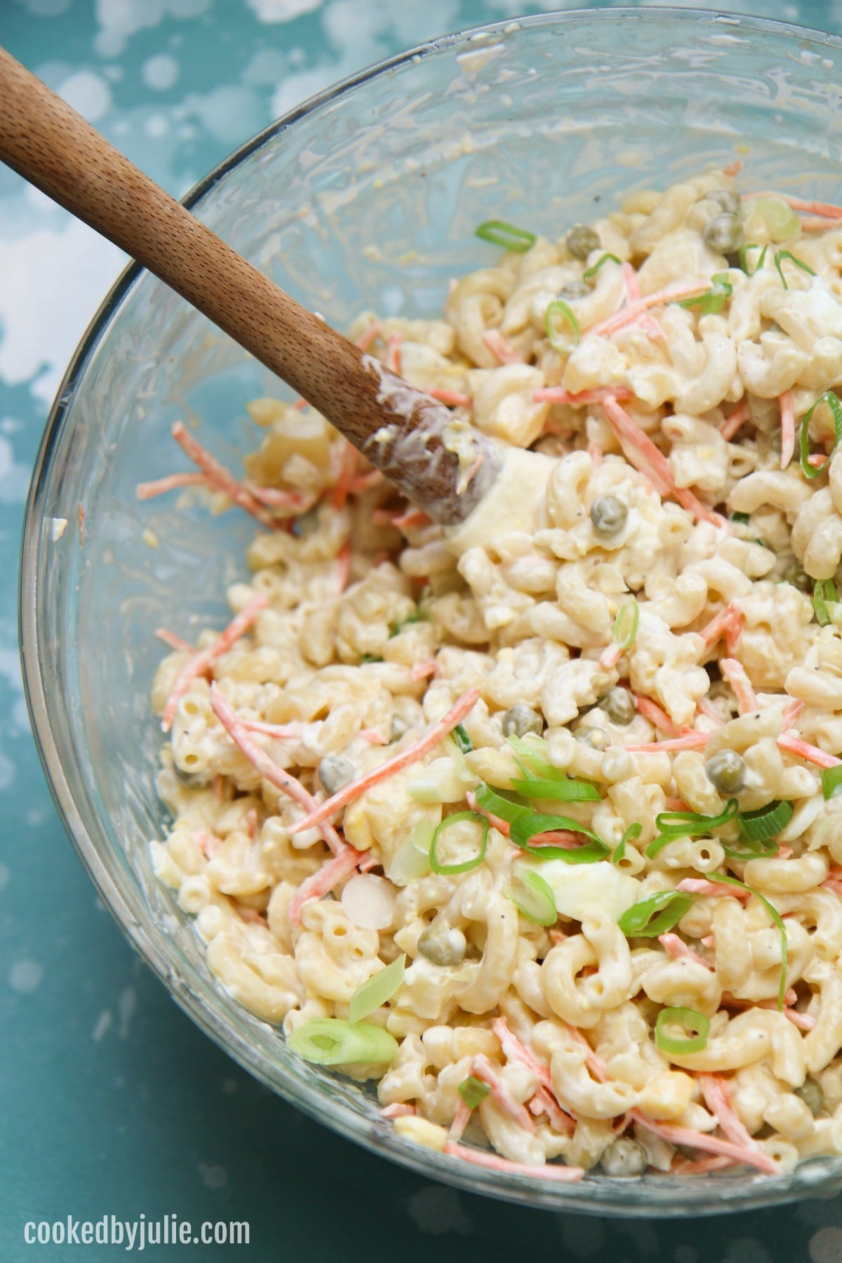 Hawaiian macaroni salad in a glass bowl with a spatula inside the bowl.