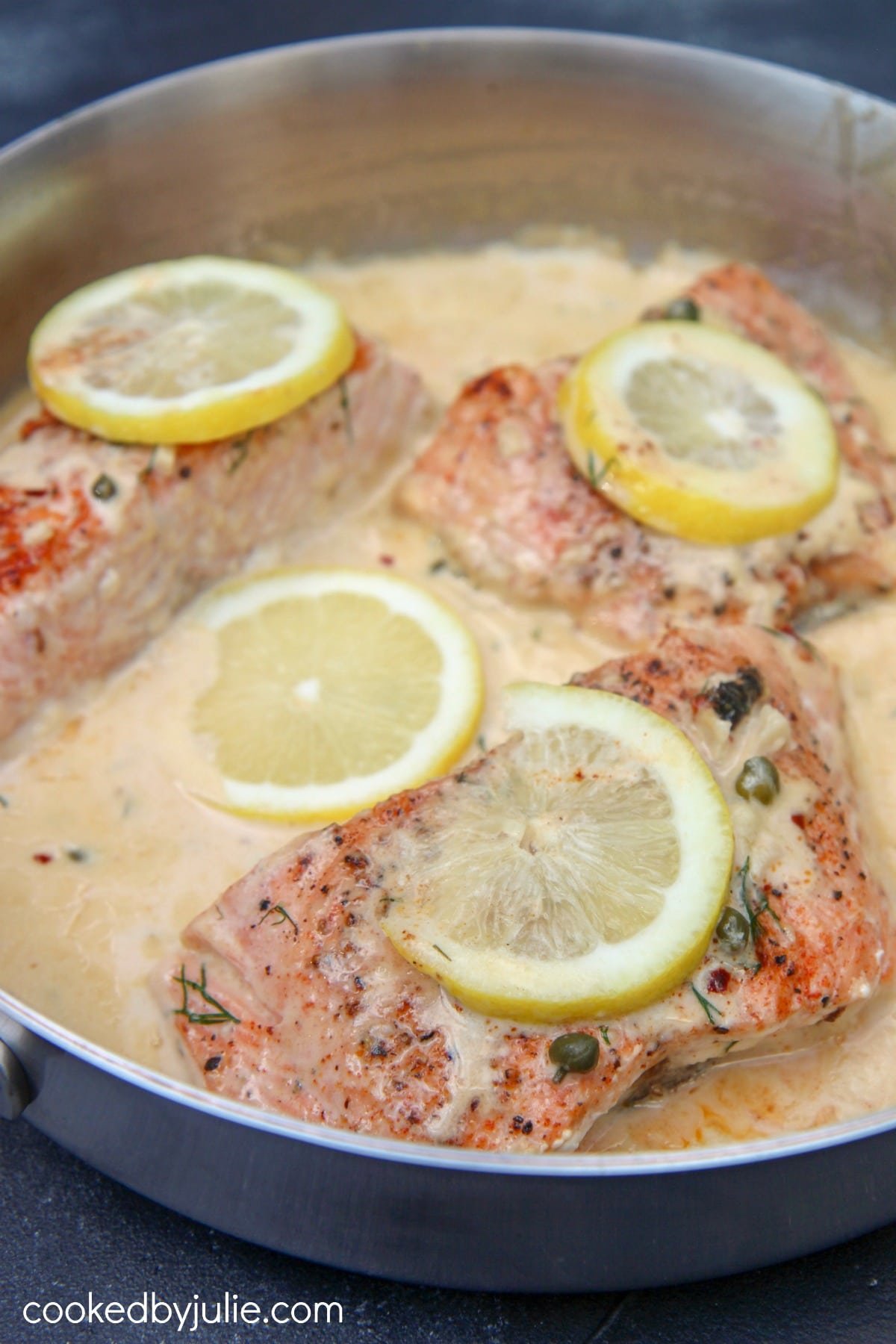 salmon with a creamy lemon sauce in a stainless steel skillet