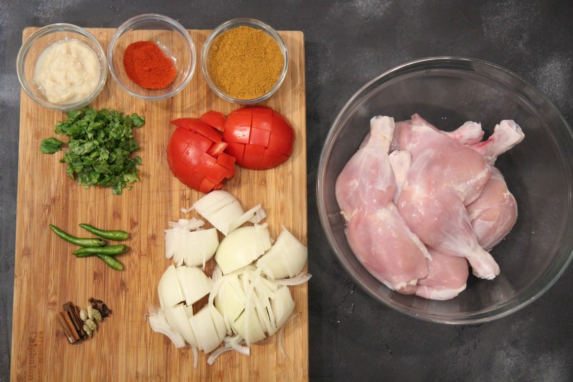 Chicken, onions, tomatoes and spices on a cutting board