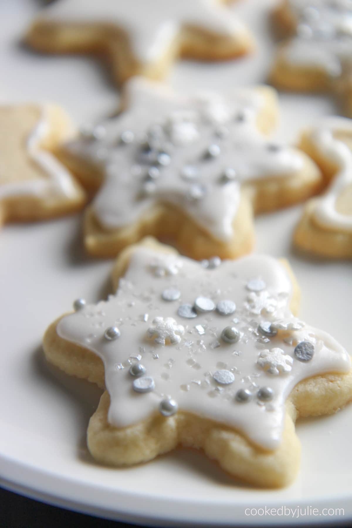 six cut out sugar cookies on a white plate. 