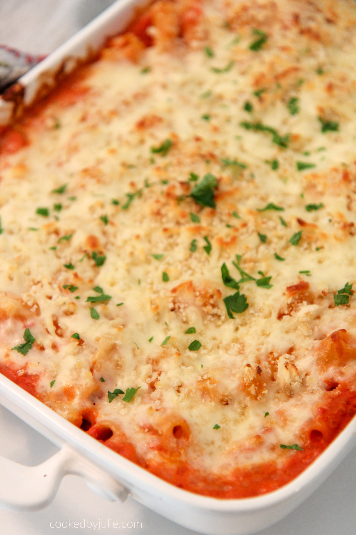 olive garden baked ziti in a white casserole dish with fresh parsley on top.