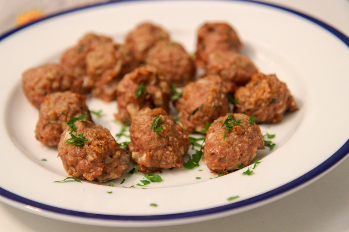 a white and blue plate of turkey meatballs with fresh parsley 