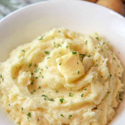 mashed potatoes in a bowl with butter and fresh parsley