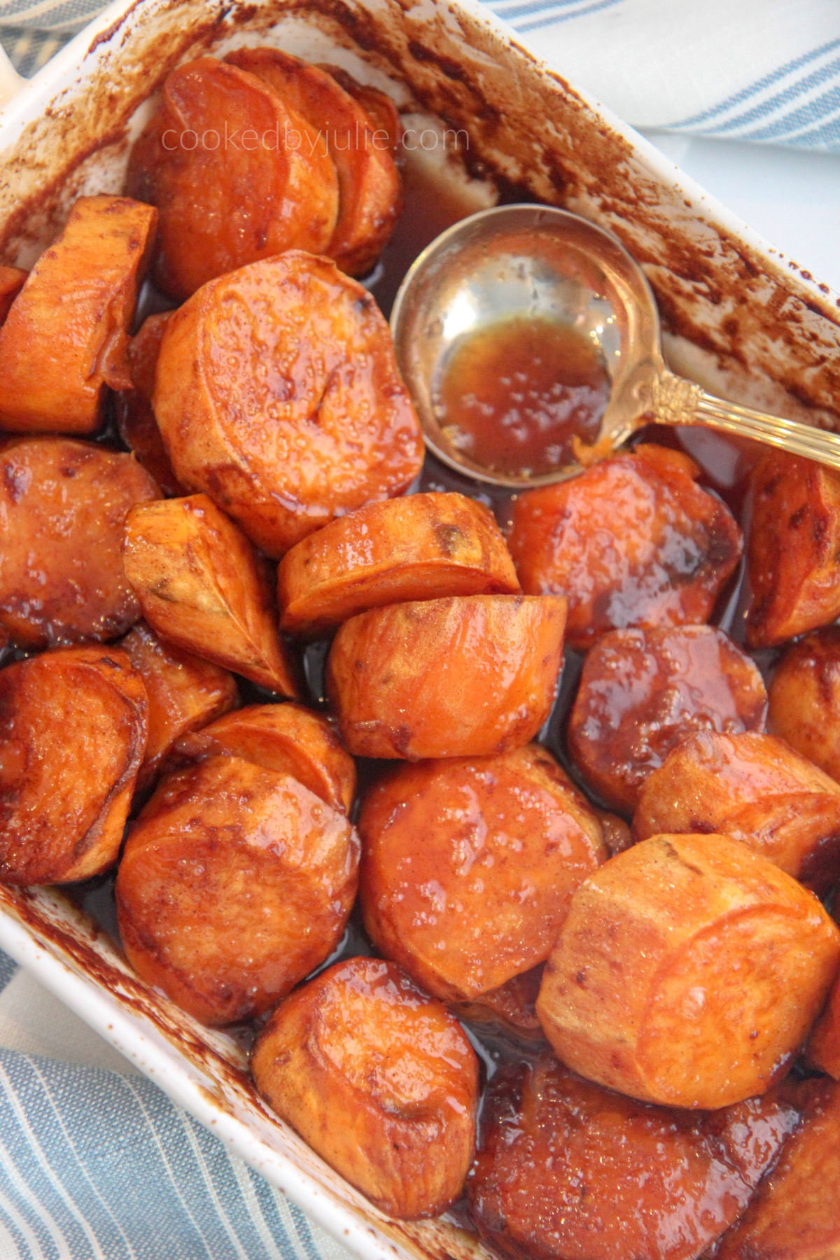 baked candied yams in a white baking dish and gold spoon