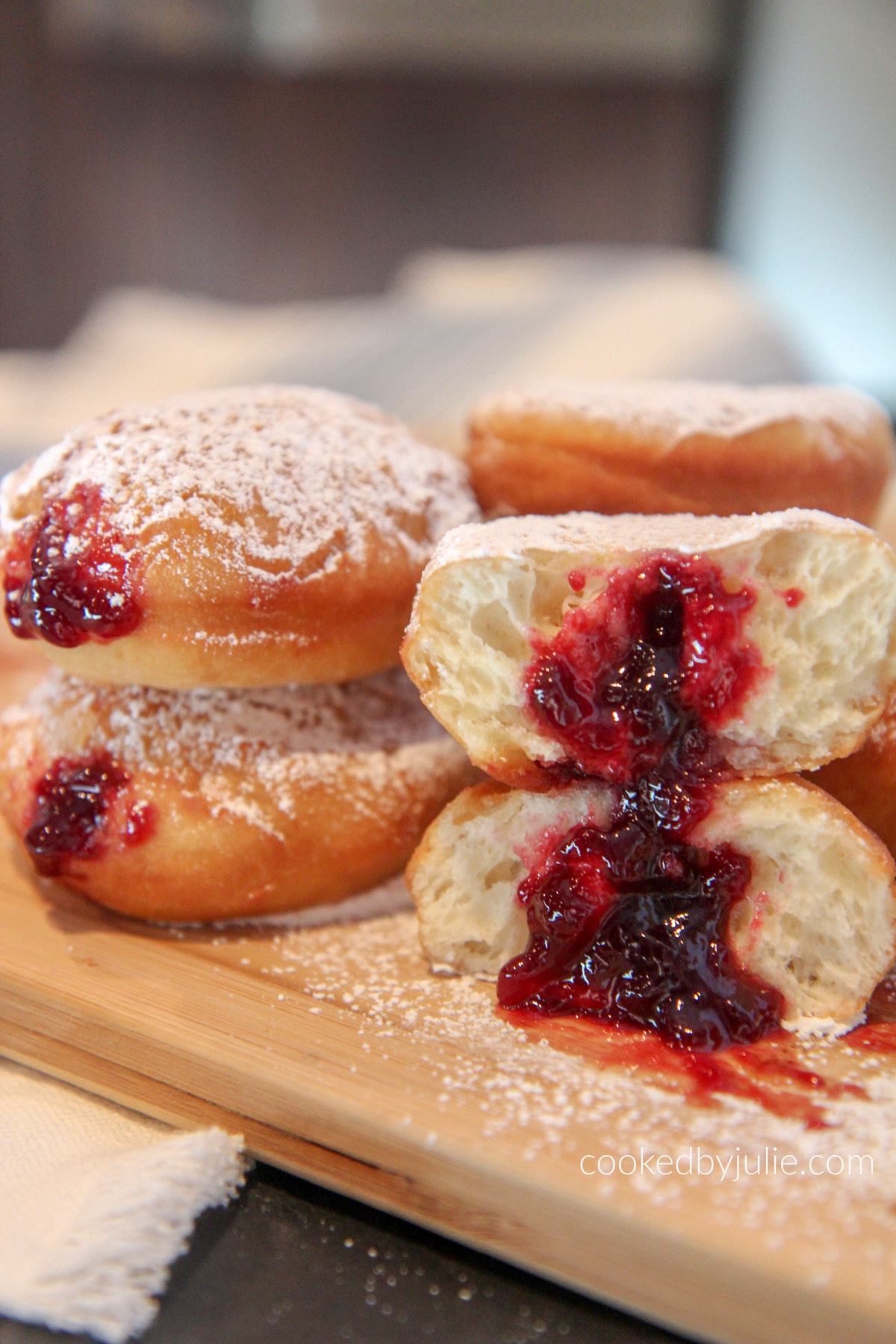powdered sugar jelly donuts cut in half with jelly oozing out 