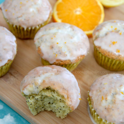 orange lemon poppy seed muffins on a wooden board with orange slices