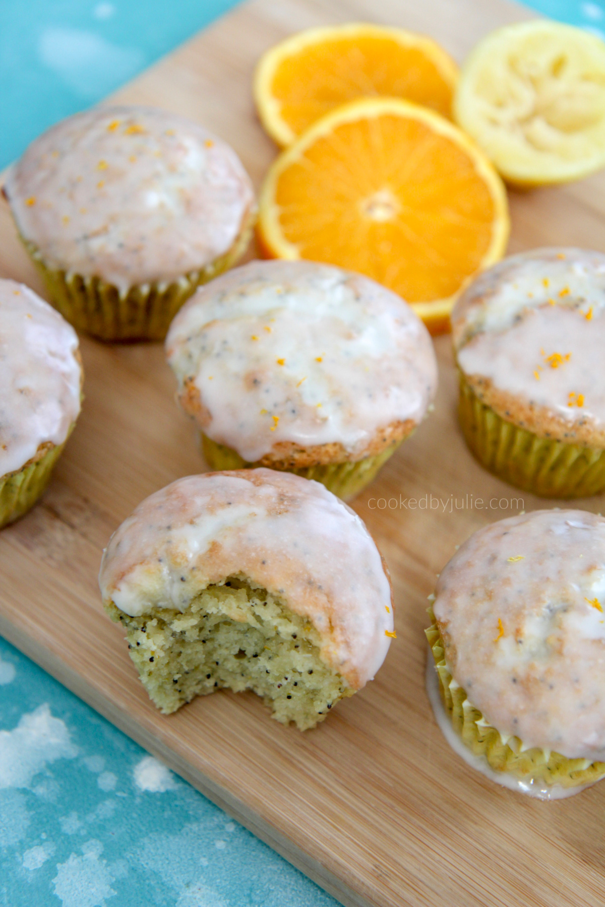 orange lemon poppy seed muffins on a wooden board with orange slices 