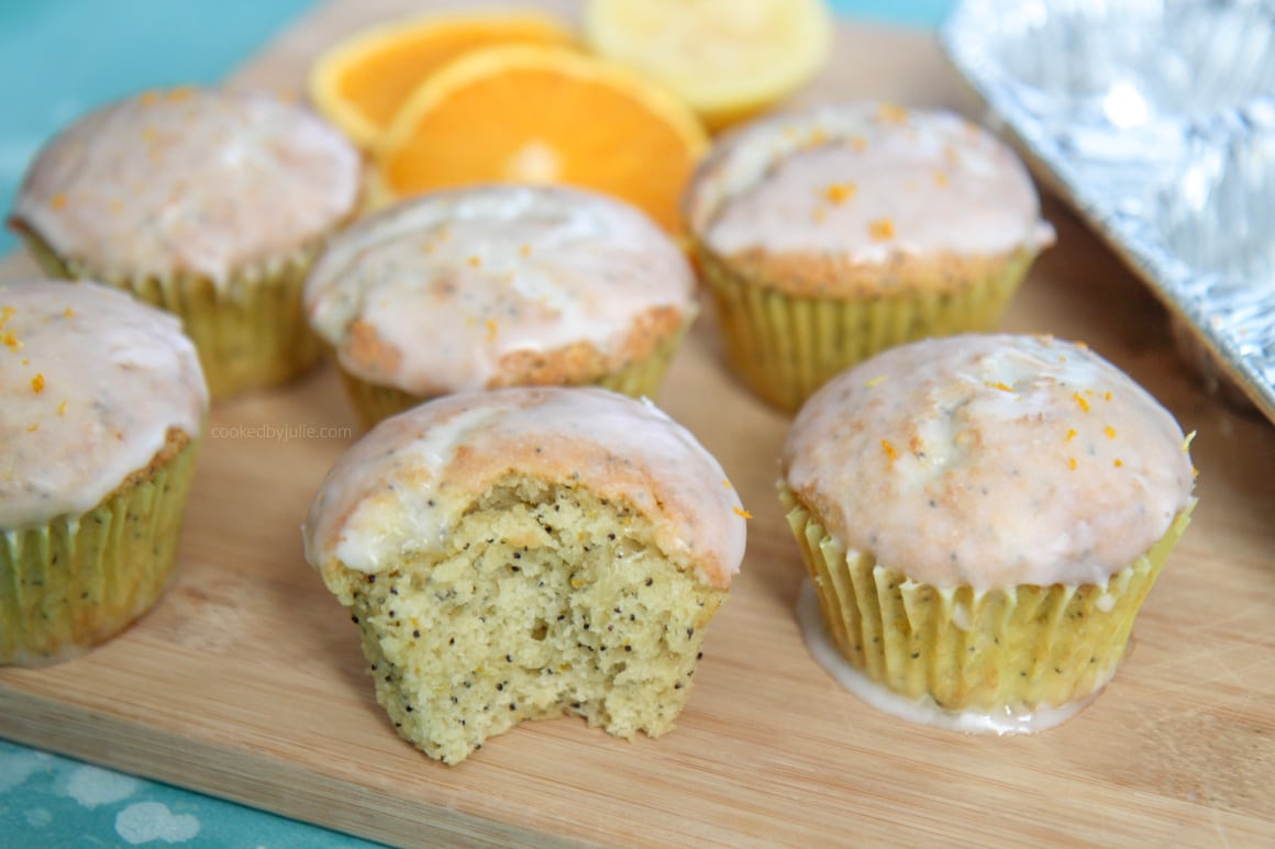 half of a orange lemon poppy seed muffin on top of a wooden board. 