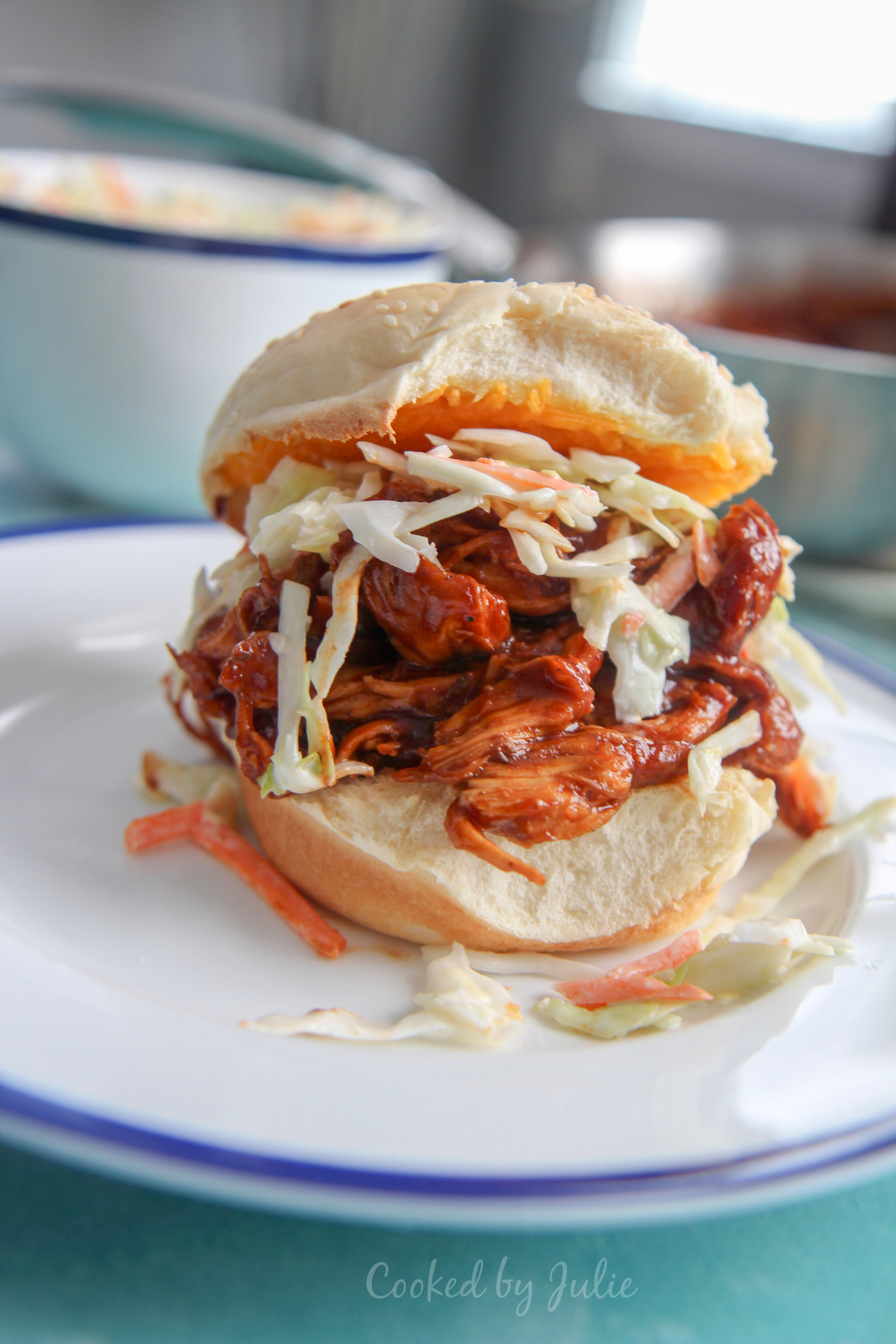 bbq pulled chicken sandwich on top of a white plate with pieces of coleslaw on the plate
