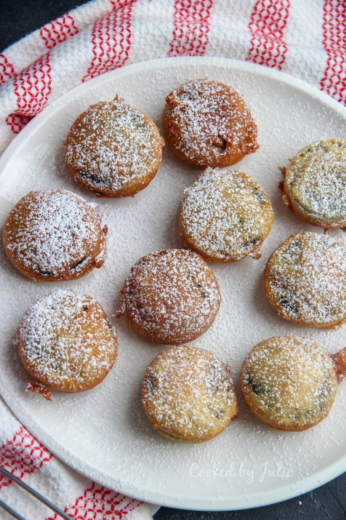 deep fried oreos with powdered sugar on a white plate and red and white towel on the side 