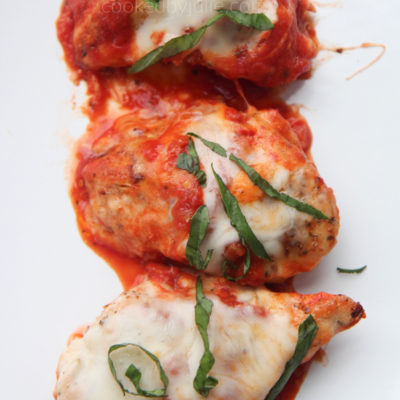 3 grilled chicken servings with sauce, cheese, and basil served on a white plate