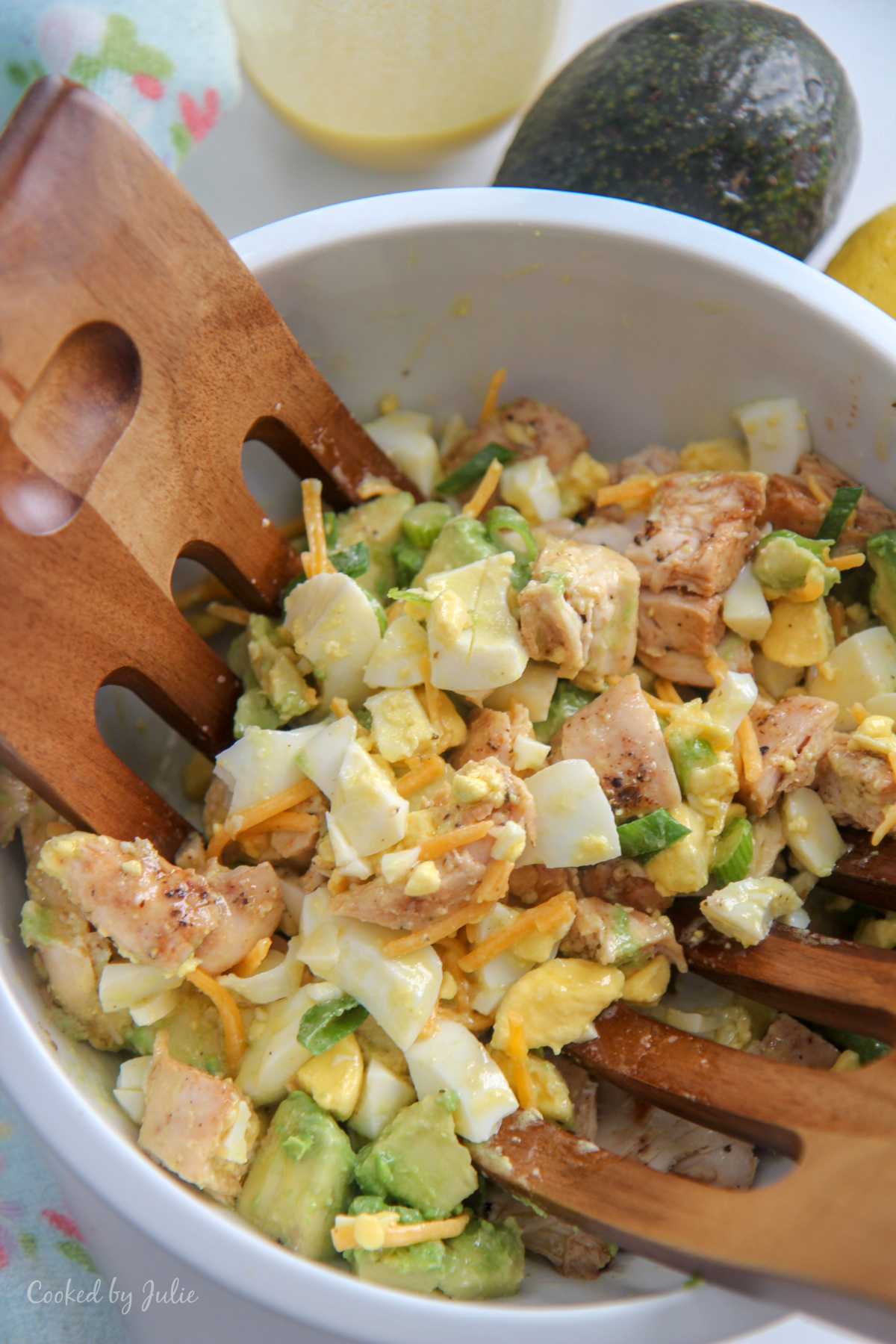 avocado chicken salad in a white bowl and wooden salad mixers