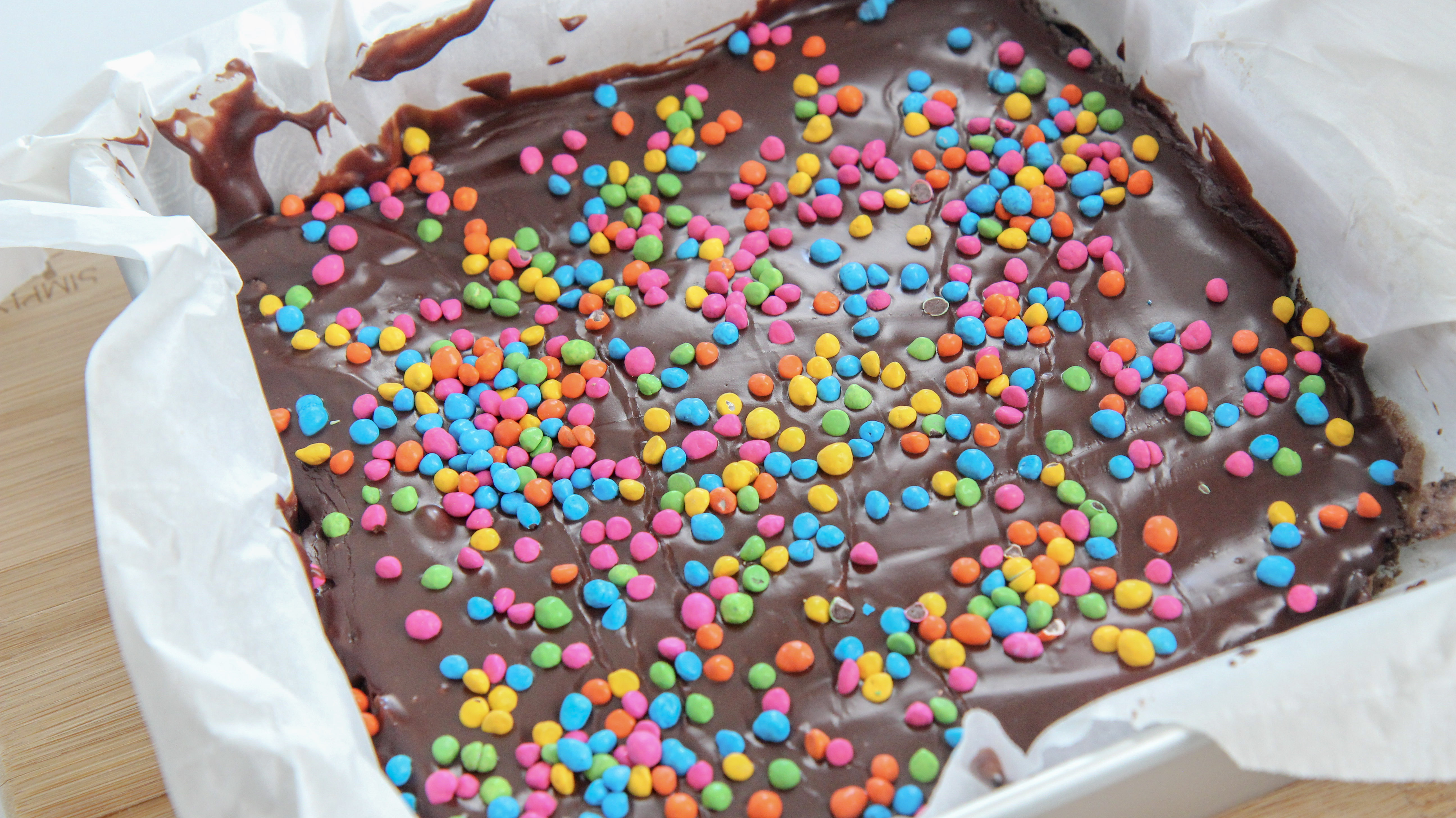 cosmic brownies in a lined 9x9 baking dish with parchment paper