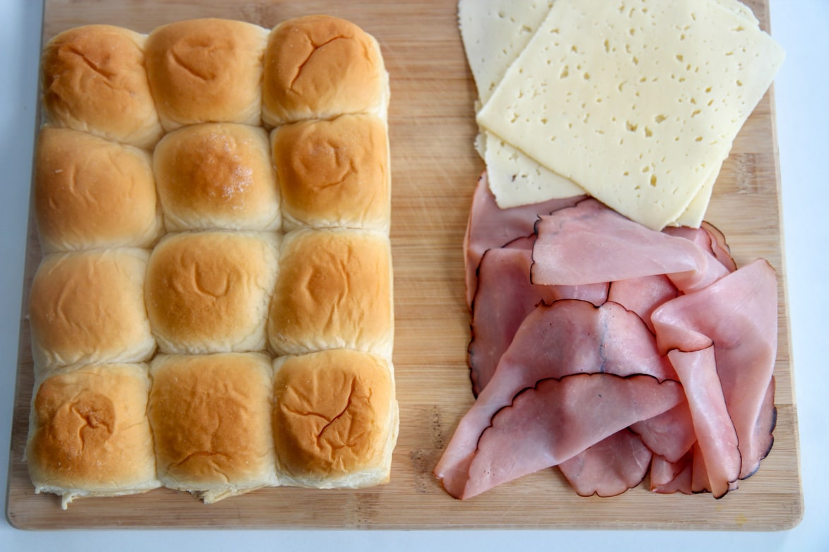 Hawaiian soft rolls with ham and cheese on a wooden board