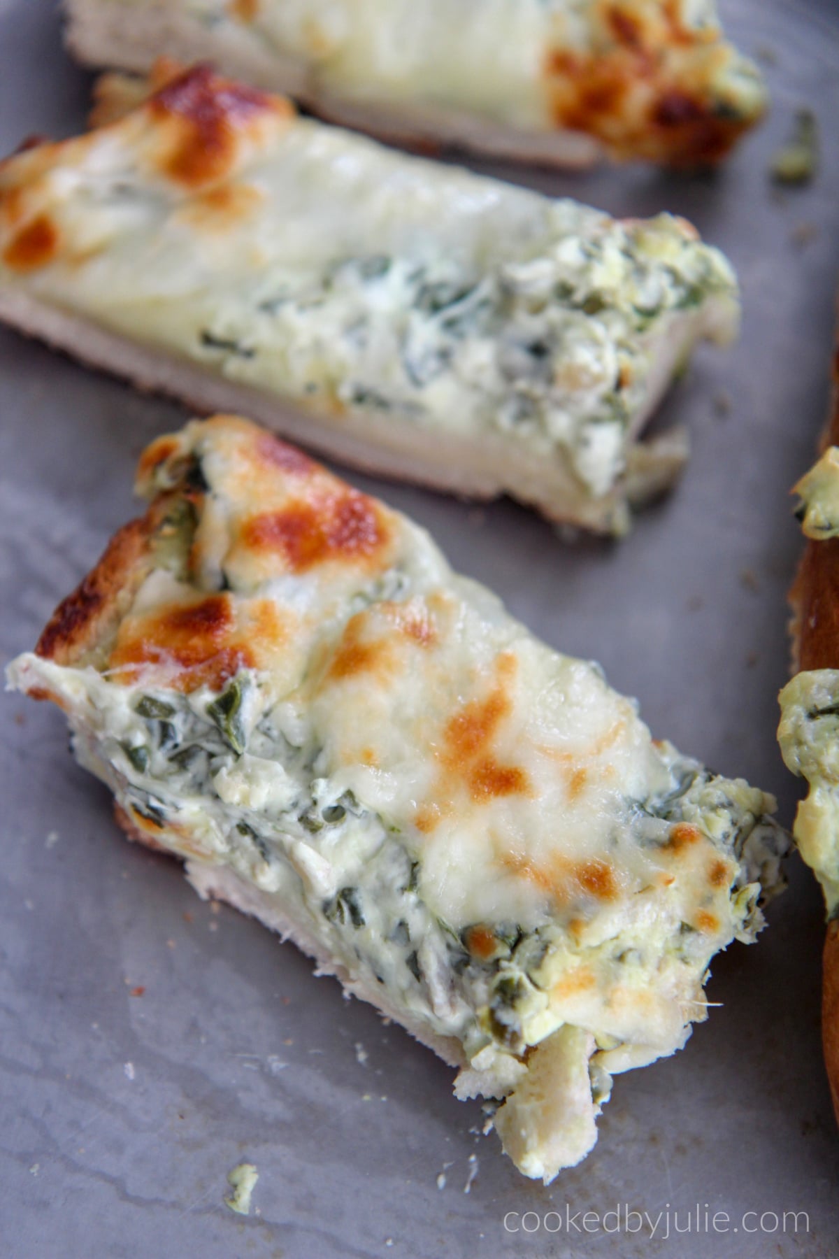 a couple slices of spinach artichoke cheese bread on a baking sheet 