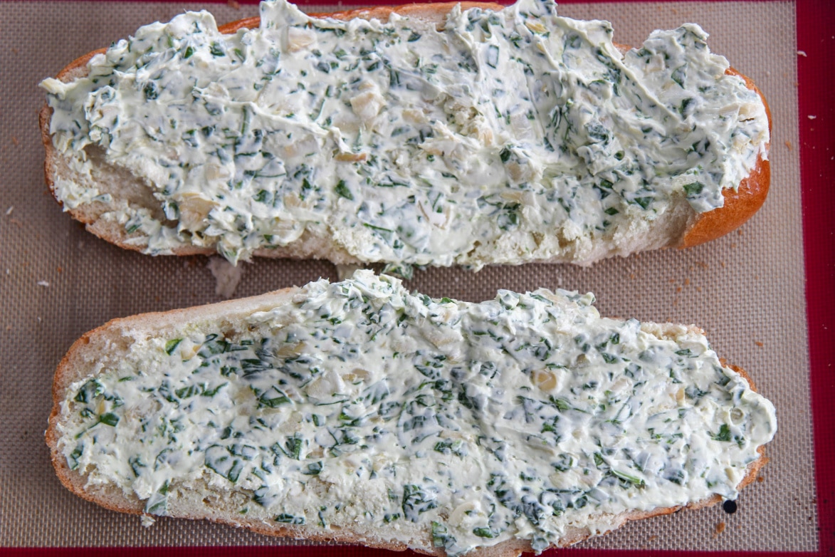 French bread slices smeared with spinach artichoke mixture 