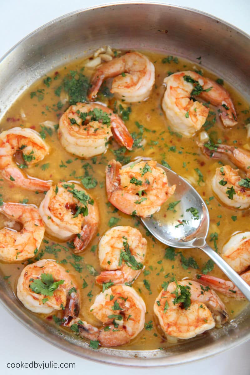 shrimp scampi in a skillet with a spoon and parsley