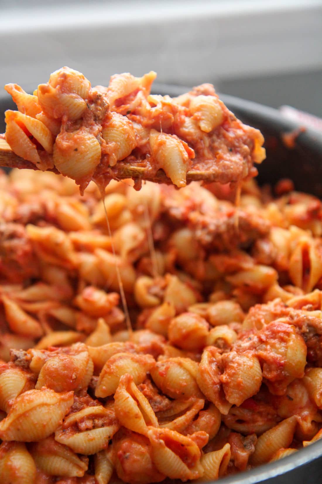 a spoonful of beef and shells over a skillet 