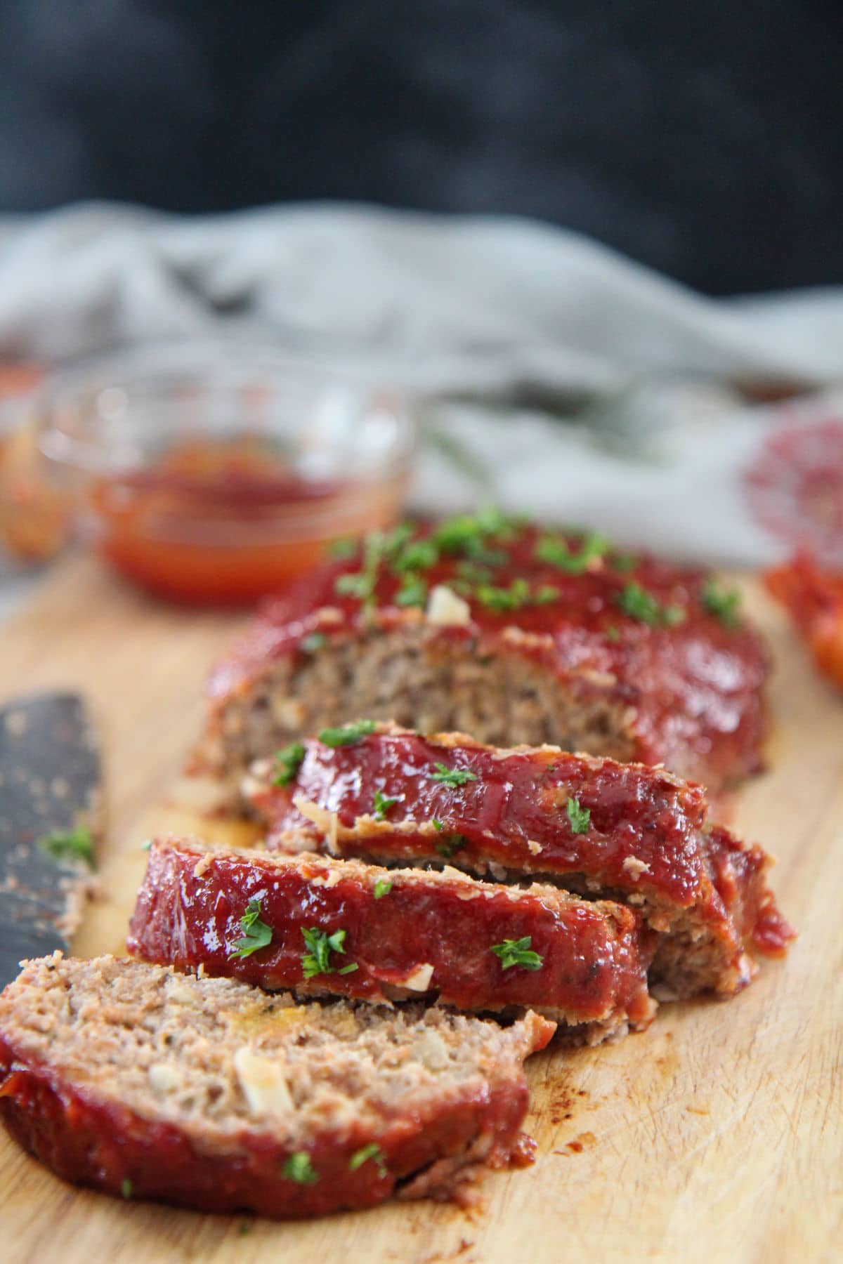 slices of turkey meatloaf on a wooden board with ketchup on the side