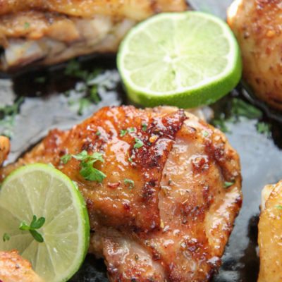 bone in chicken thighs in a cast iron skillet with lime wedges