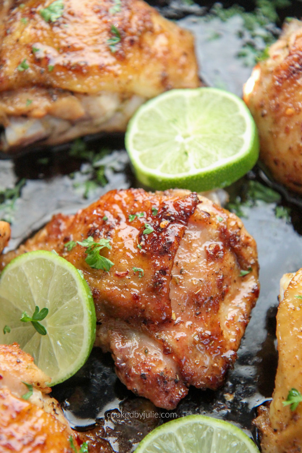 bone in chicken thighs in a cast iron skillet with slices of lime 