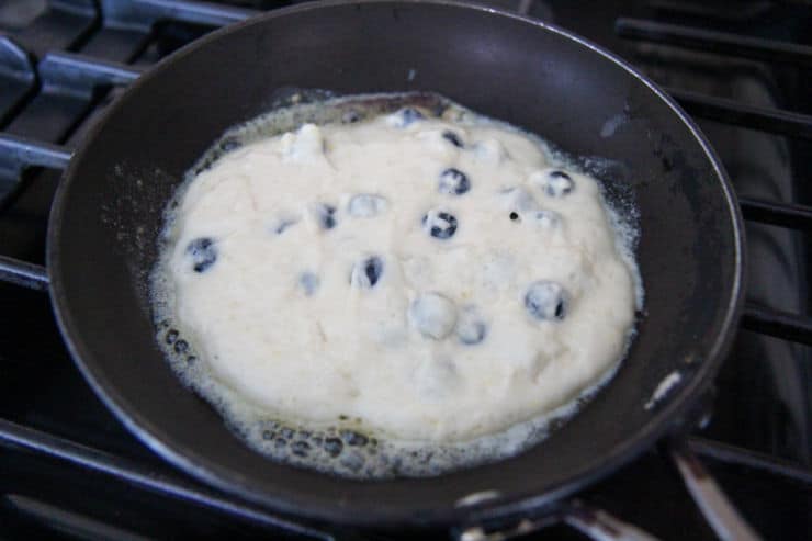 blueberry pancake cooking in a black skillet 