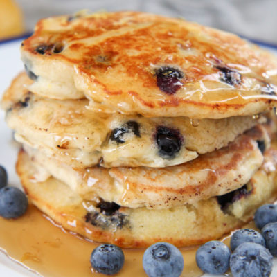 stacked pancakes with syrup and blueberries on the side