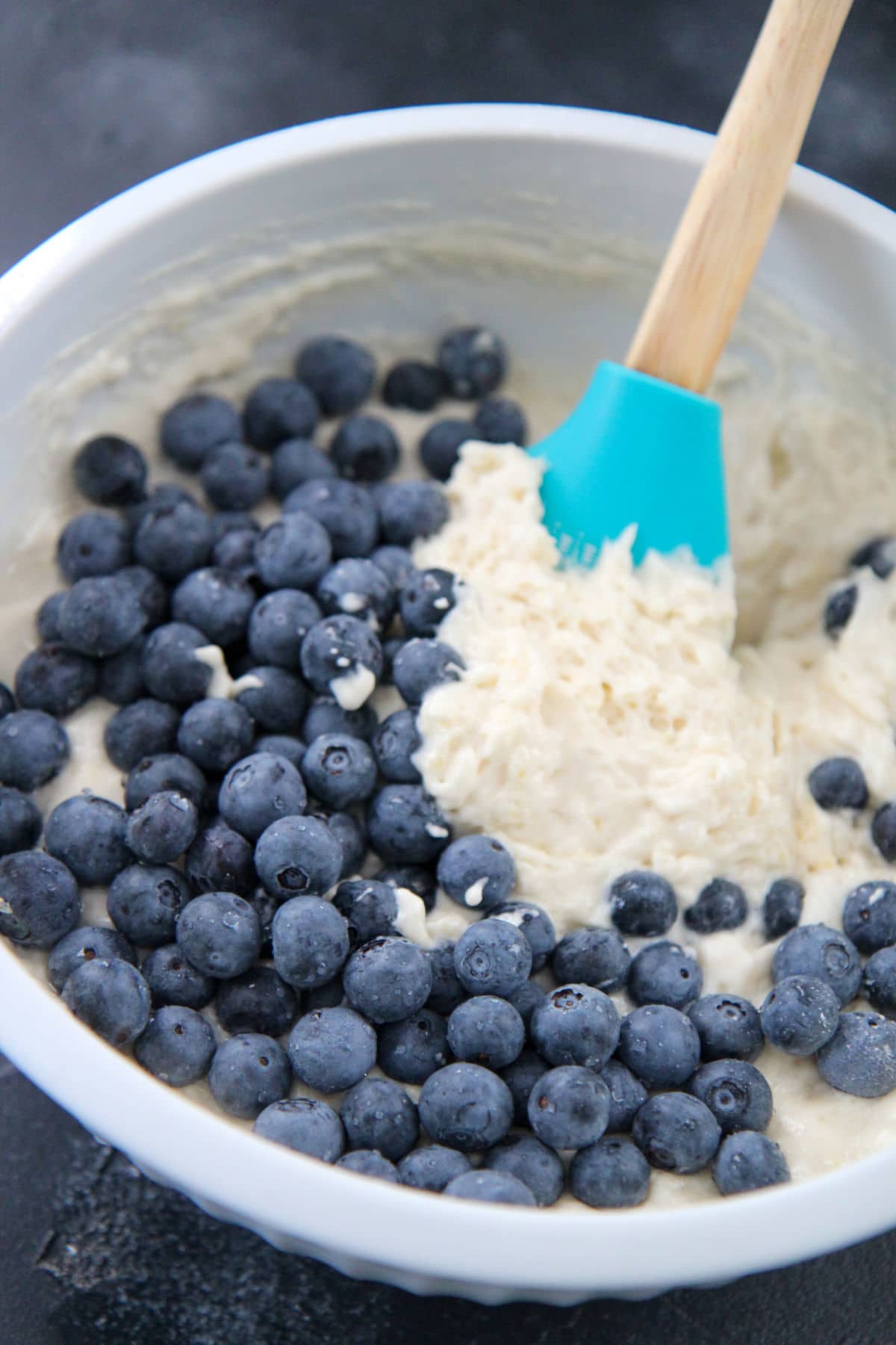 pancake batter with blueberries on the side and a spatula in a bowl 