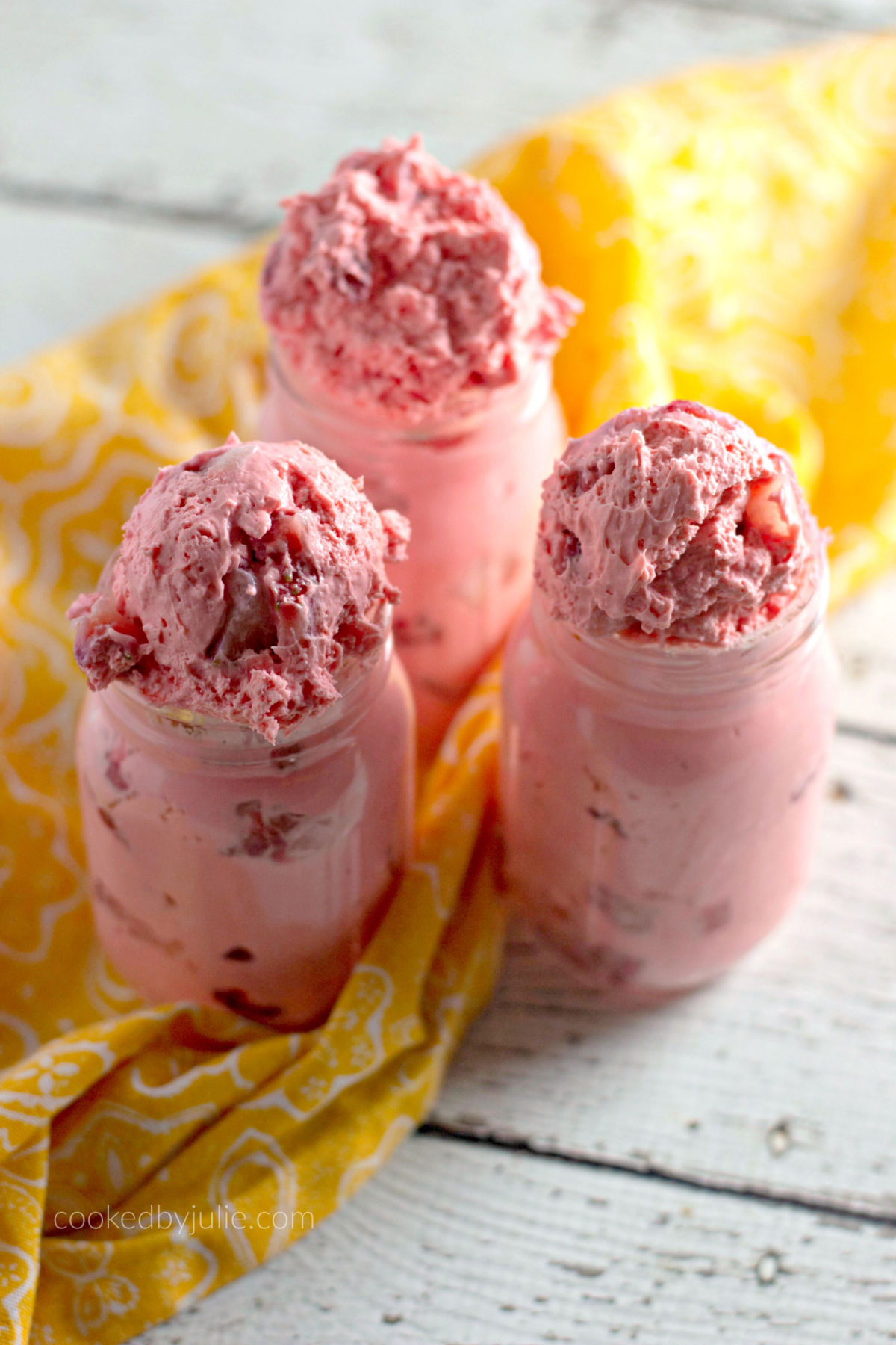 strawberry fat bombs inside mason jars with a yellow towel on the side 