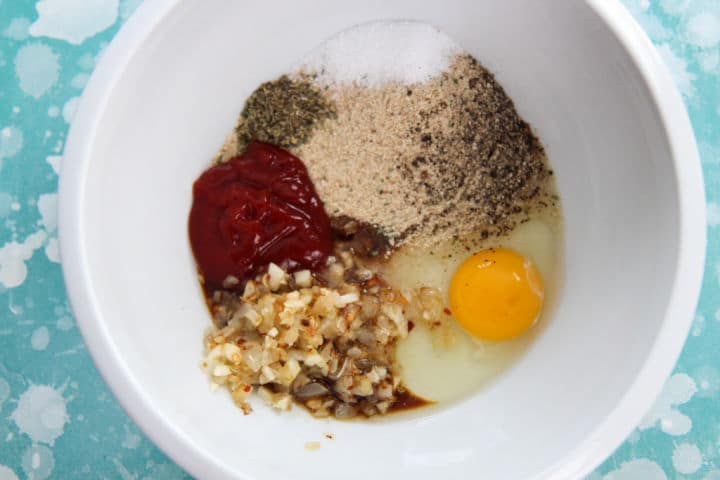 egg, ketchup, onions, seasonings, and breadcrumbs in a white bowl
