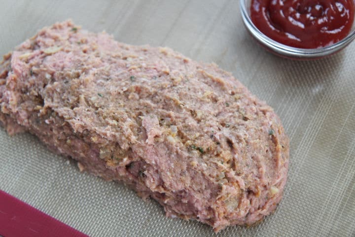 ground turkey formed into a log on a baking sheet with a side of ketchup