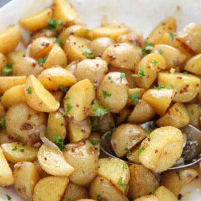 baby yellow potatoes in a white bowl with a aspoon