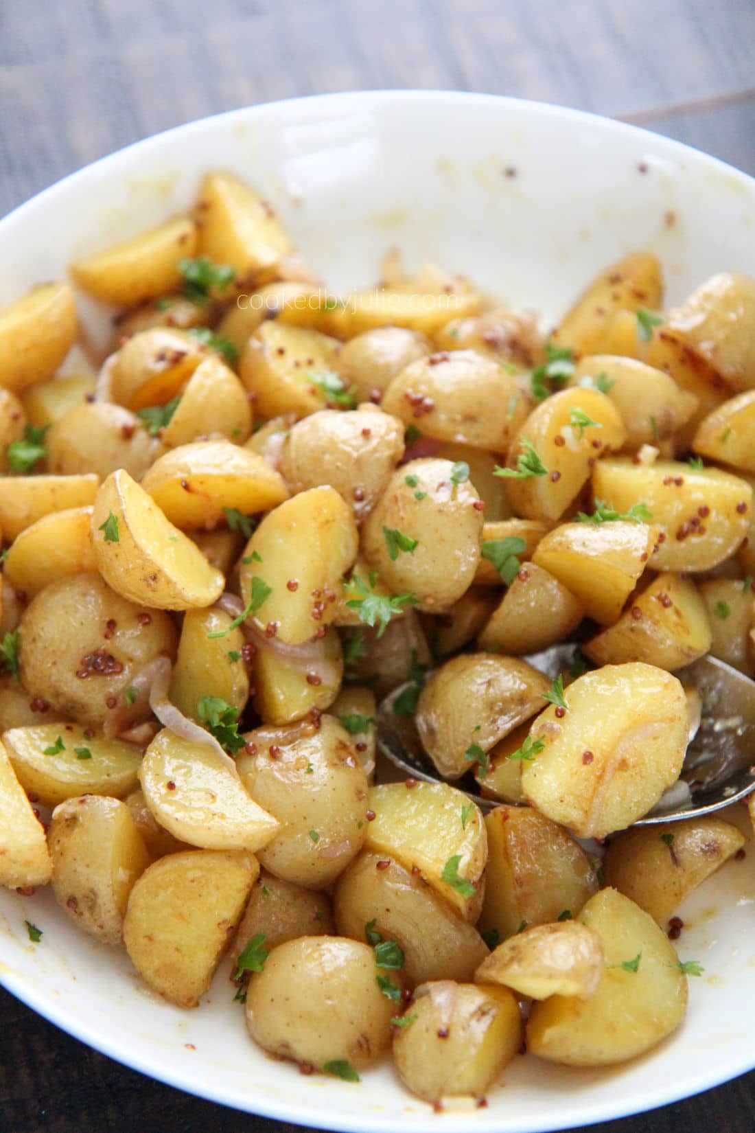 baby yellow potatoes in a white bowl with a aspoon