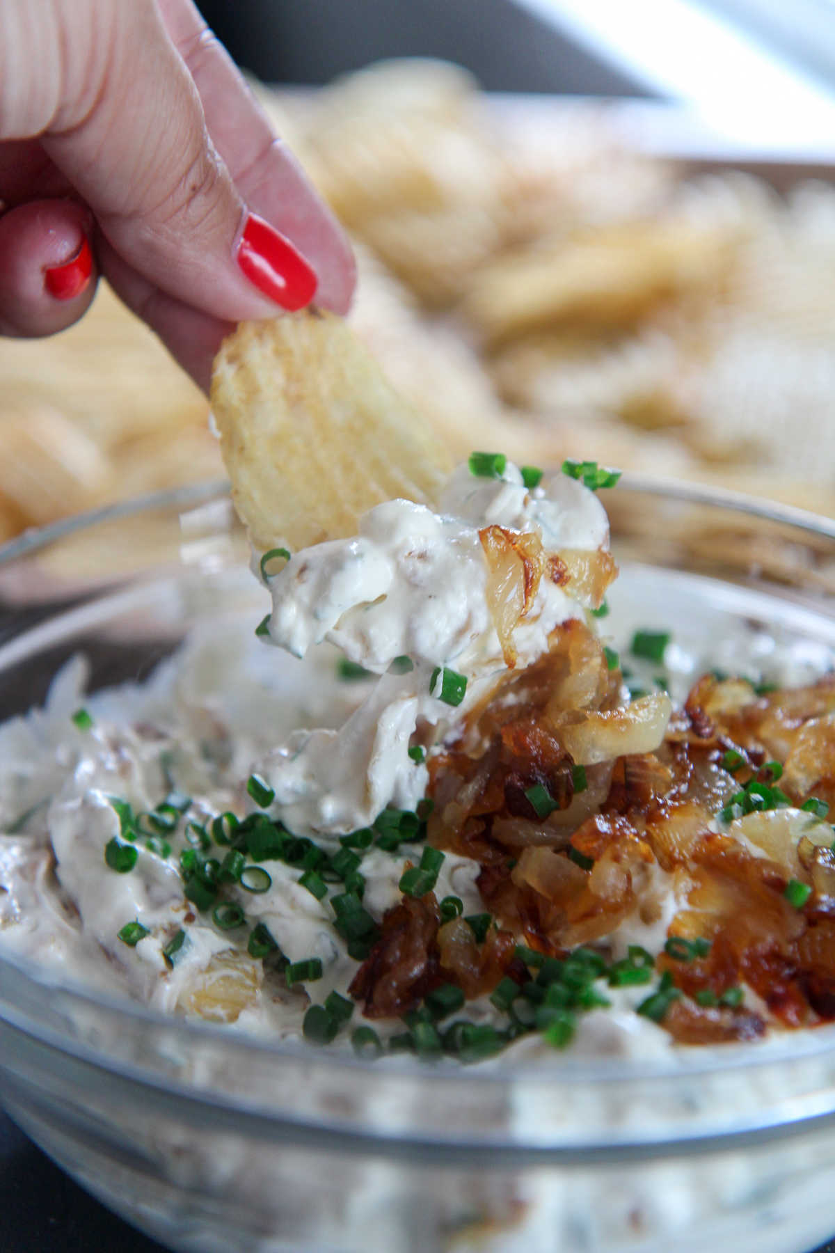 person holding a chip over a bowl of French onion dip 