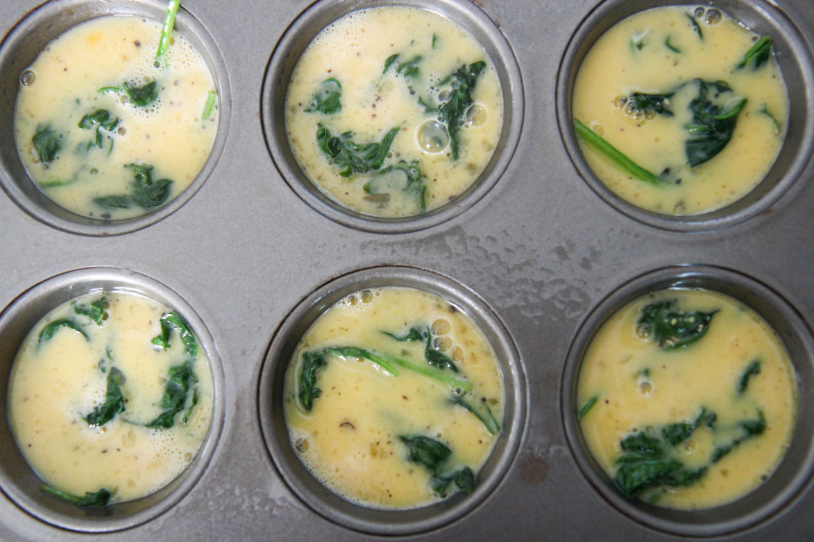 six scrambled eggs with spinach in a muffin tin