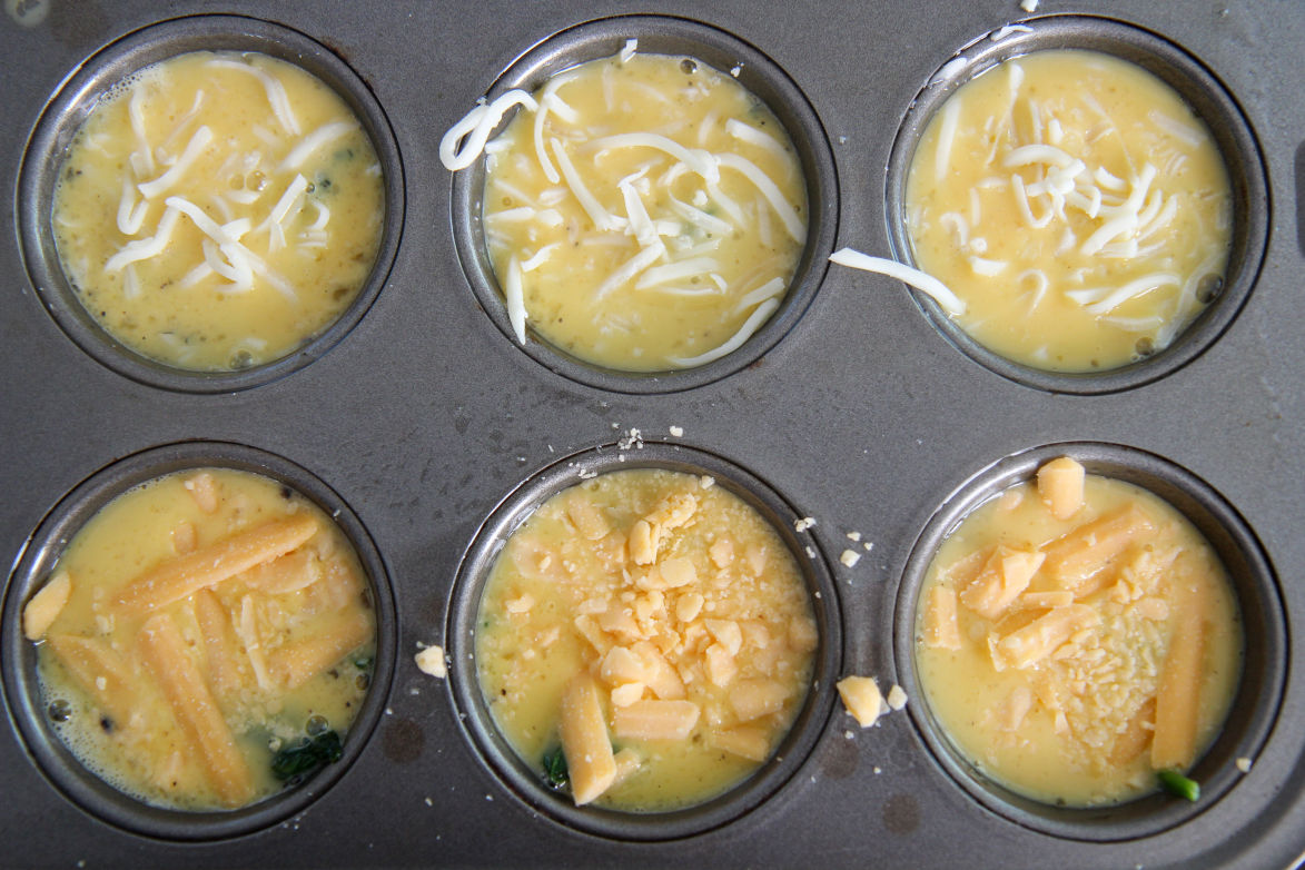 six scrambled eggs with spinach and cheese in a muffin tin 