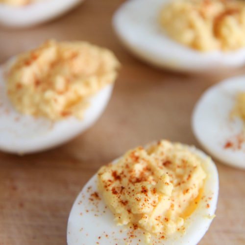 deviled eggs with paprika on a wooden board