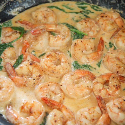 shrimp, cream sauce, and spinach, in a black skillet
