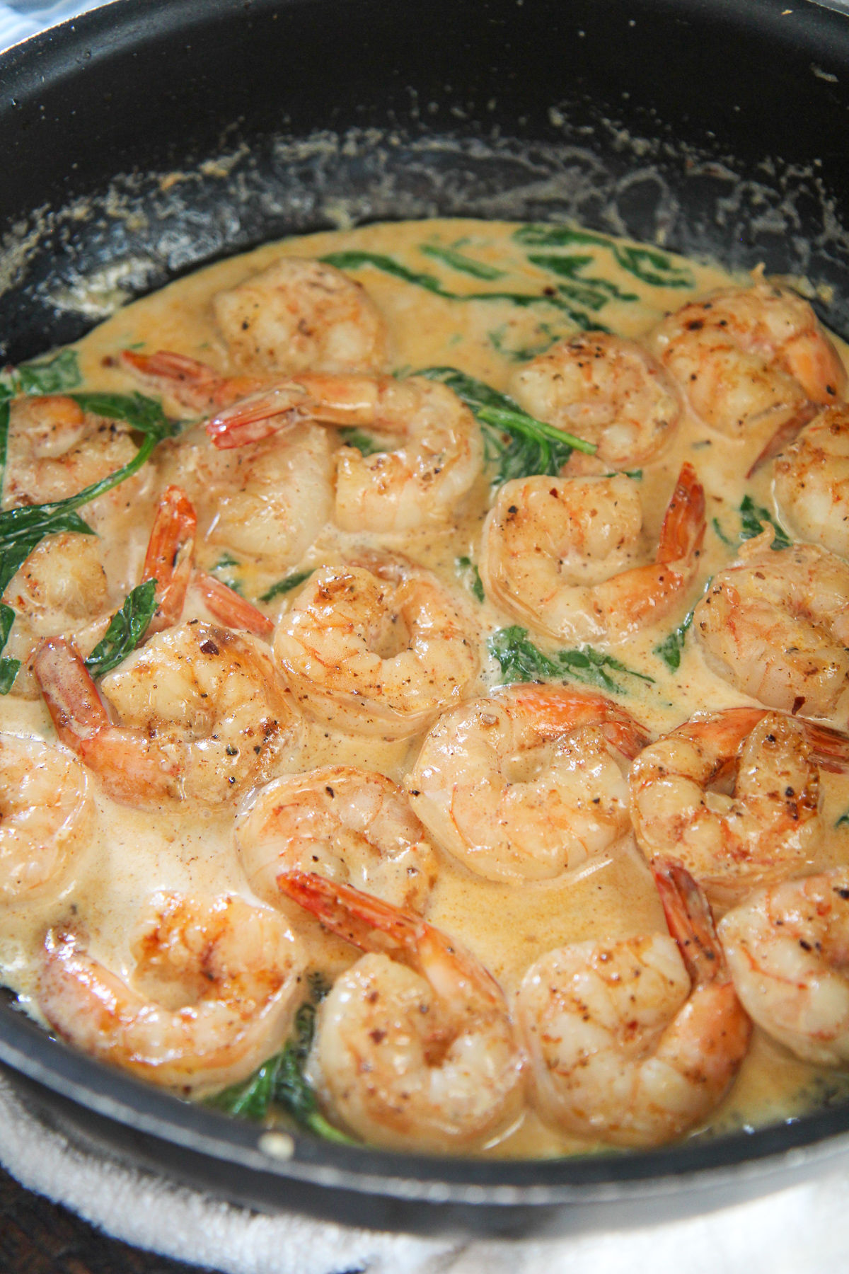 shrimp, cream sauce, and spinach, in a black skillet