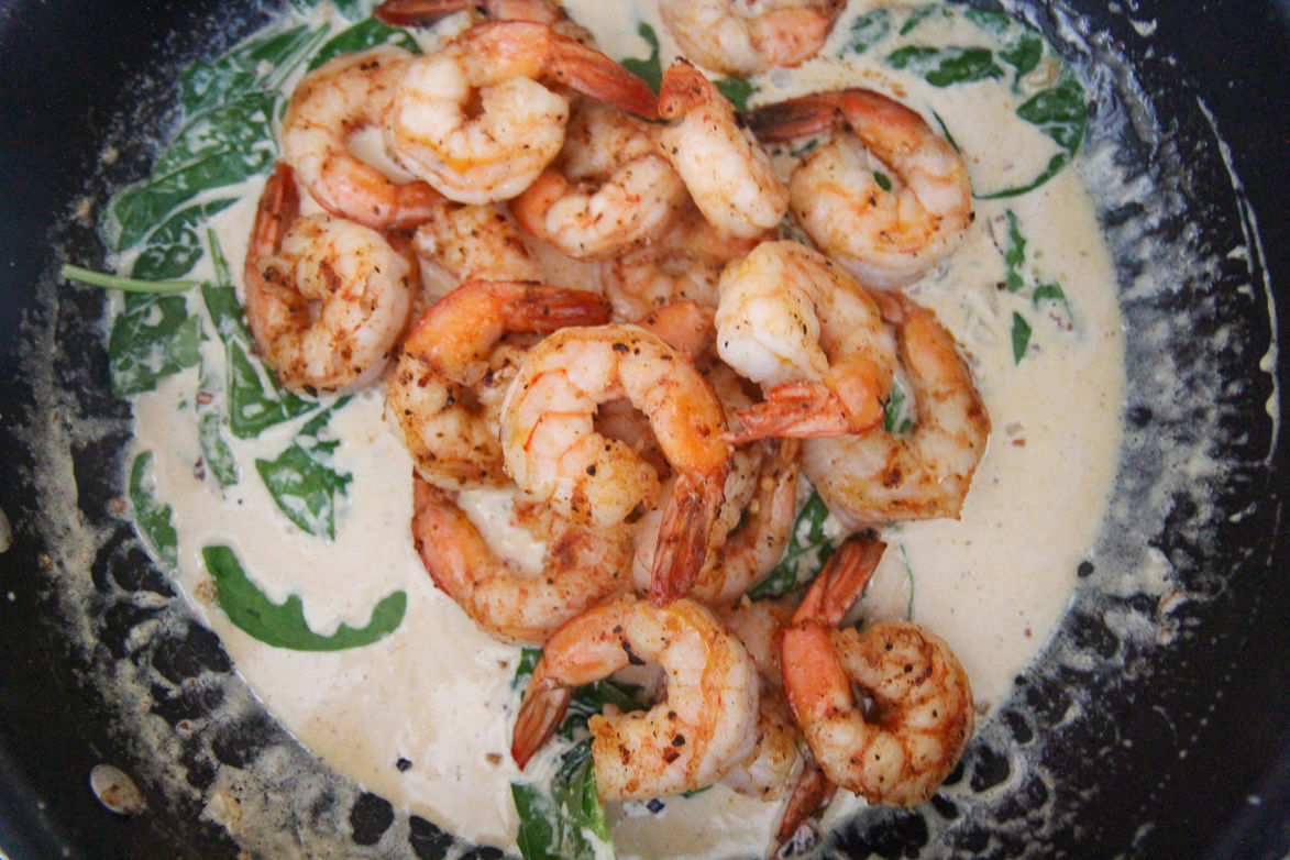 shrimp, spinach, and cream sauce in a black skillet 